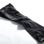 High-quality photo of neatly folded dark denim pants on a white background, showcasing fashion details.